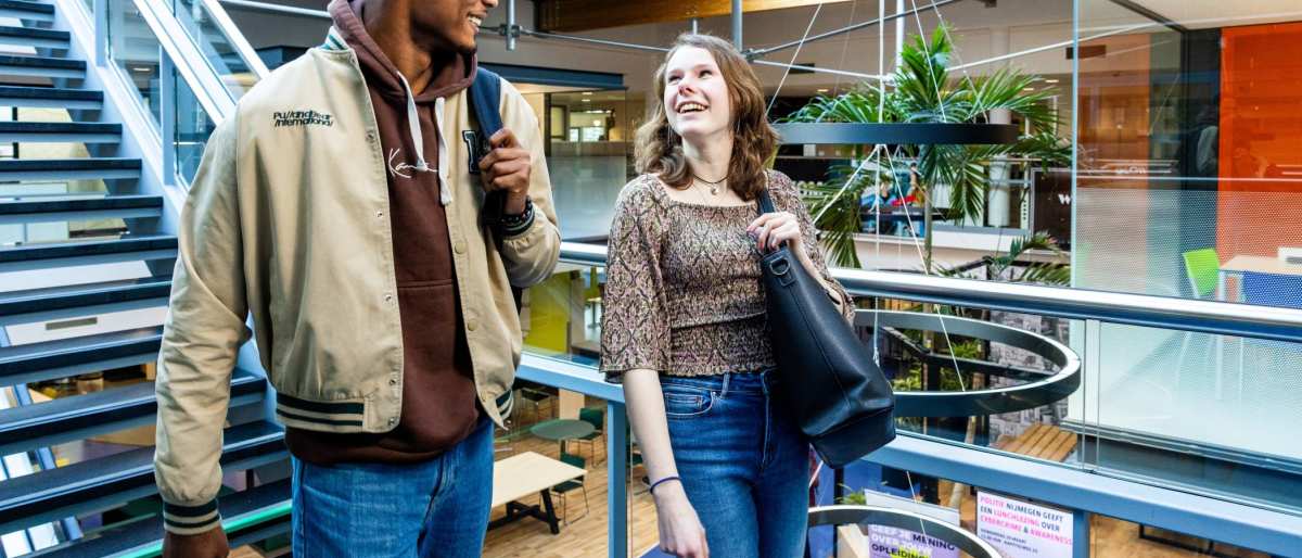 Studenten Learning and Development in Organisations (Opleidingskunde) lopen lachend de trap af in Nijmegen