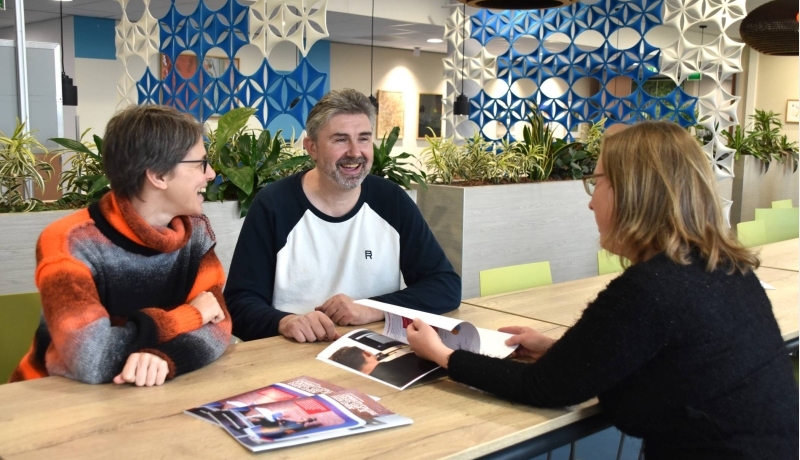 3 mensen in gesprek. Een foto met daarop de handleiding Leef je eigen leven, onderdeel van het project Capability College, Volwaardig Leven met Autisme