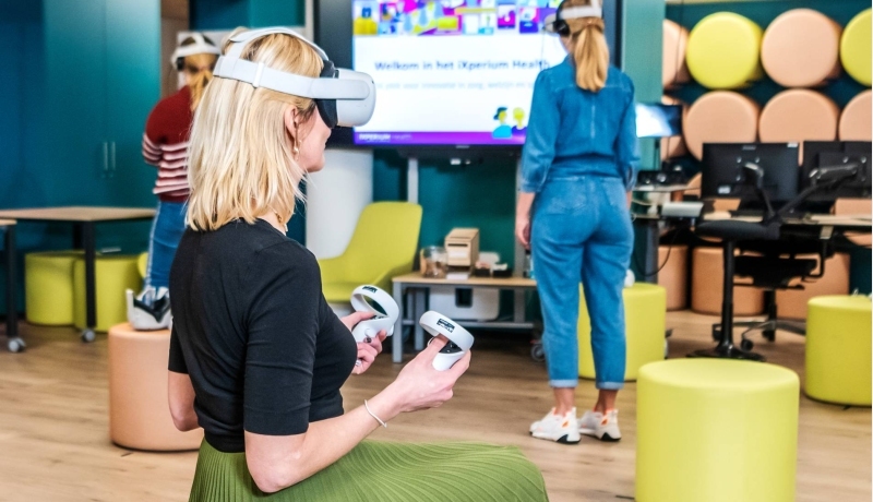 Foto van iXperium Health, waar 2 studenten en een docent een VR-bril op hebben.