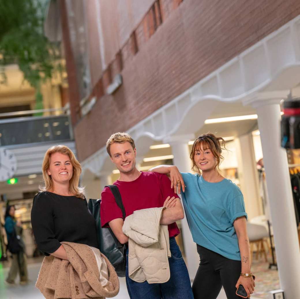 Groep studenten staat in hal met jassen uit en lachen