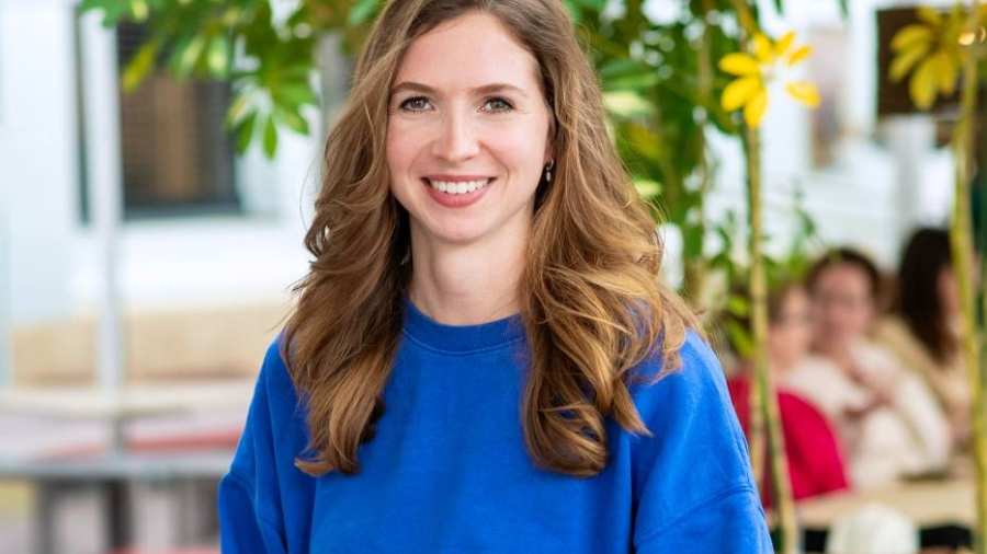 Lachende vrouw met blauwe trui, kijkend naar de camera.