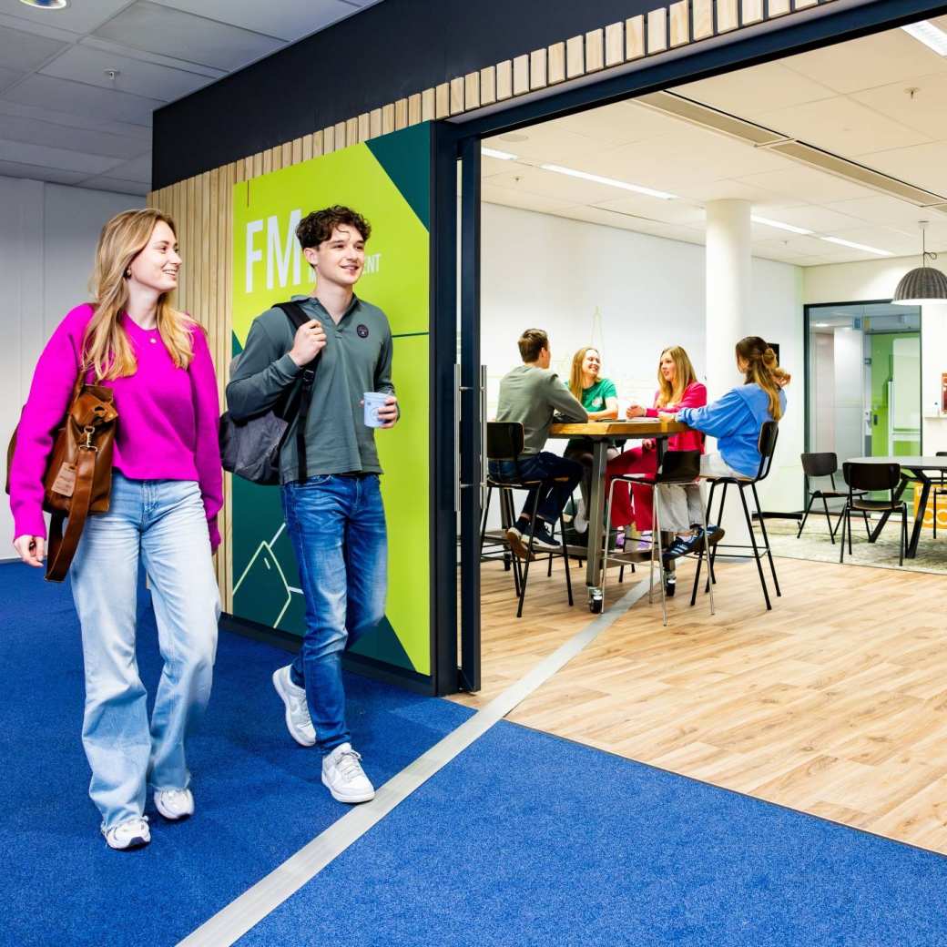 Studenten Facility Management lopen voor de studio van de opleiding