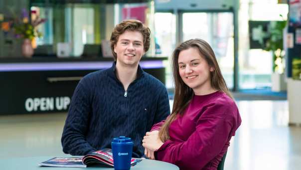 studenten hbo bedrijfskunde zitten aan tafel en kijken in de camera