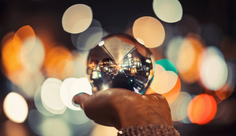 Een glazen bol met een stad op een hand met kleurige achtergrond lichtjes