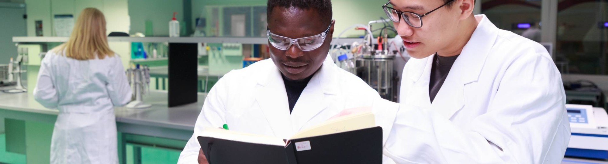 Studenten master Life Sciences Alain Barhasima en Dat Le werken in een biologielab. Op de rug Lisan Scholten