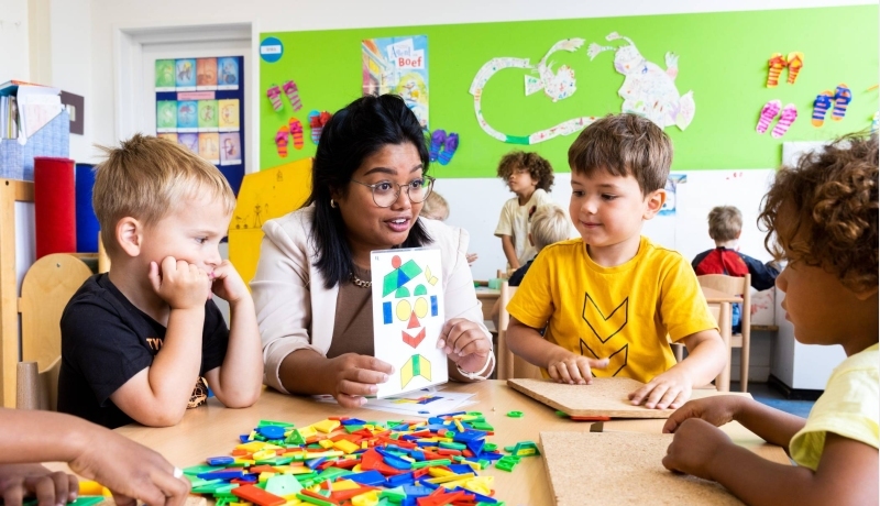 Meester kijkt mee bij kinderen in de klas