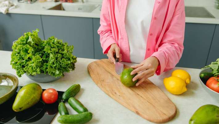Een vrouw met een roze blouse snijdt een limoen. Gezond eten van kankerpatiënten. Project Barbara van der Meij.