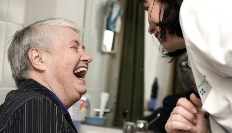 Een oudere die in gesprek is met een hulpverlener in de thuissituatie