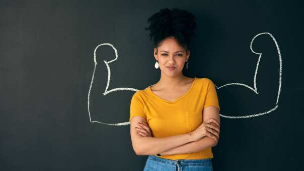 Vrouw voor schoolbord met sterke armen getekend