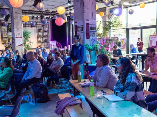 Symposium Nieuwe Wonen 2023. Mensen luisteren naar sprekers.