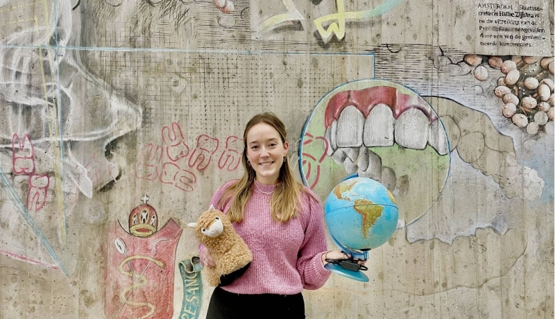 Iris Klein. student Mondzorgkunde met een wereldbol en een knuffel van een lama in haar hand.