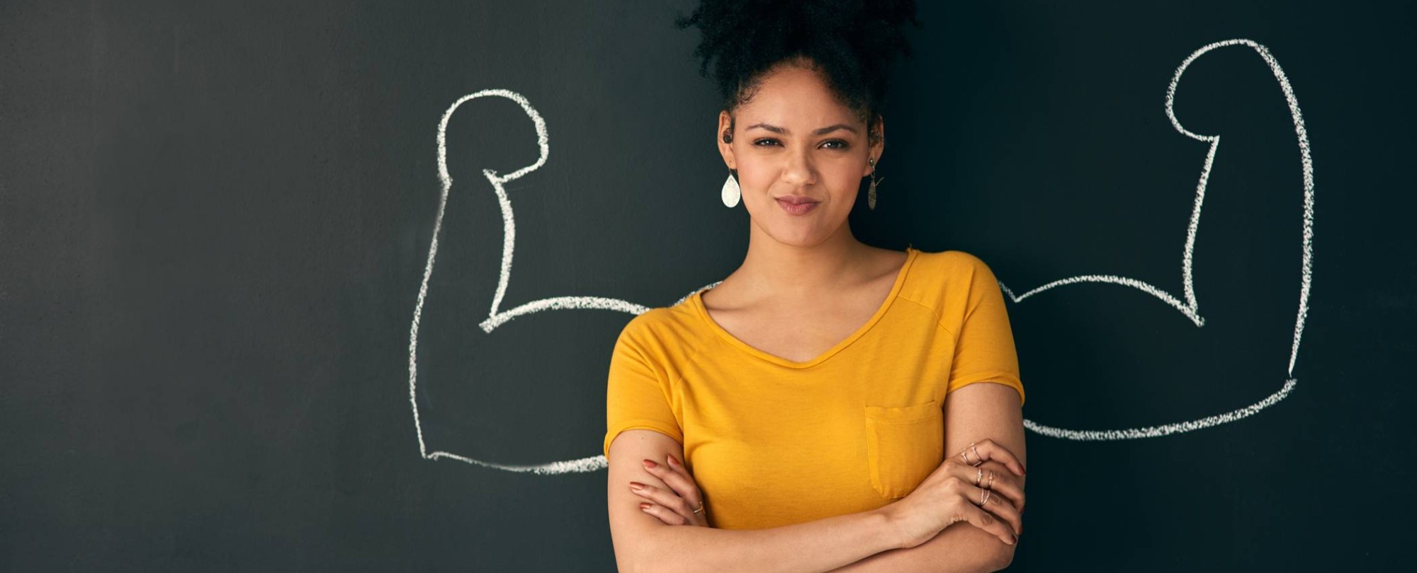 Vrouw voor schoolbord met sterke armen getekend