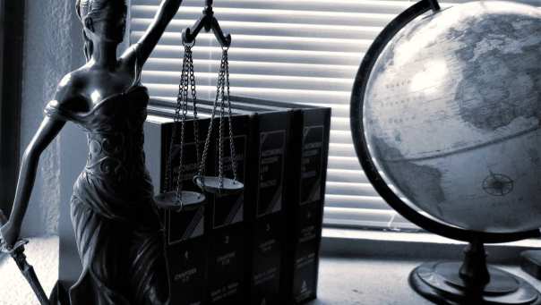 Vrouwe justitia met wettenbundels en wereldbol
