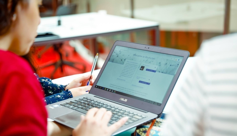 Een deeltijdstudent houdt een laptop vast met de Studielink pagina om zich aan te melden.