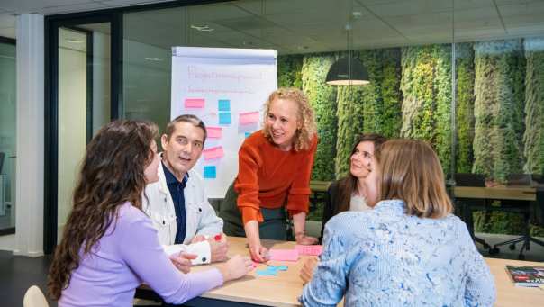 Deelnemers en docenten van de post-hbo Bedrijfskunde in overleg, lachend.