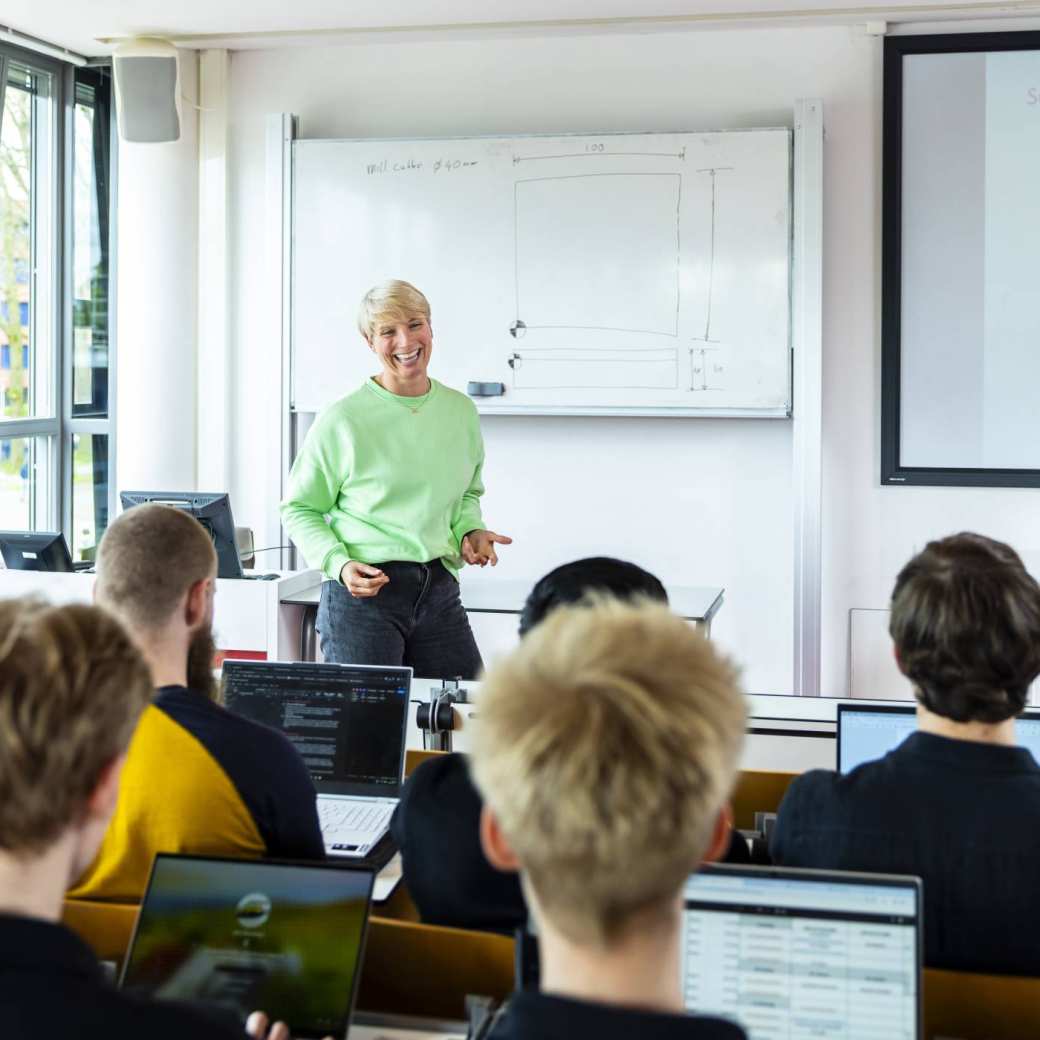 Docent HBO-ICT geeft les en glimlacht