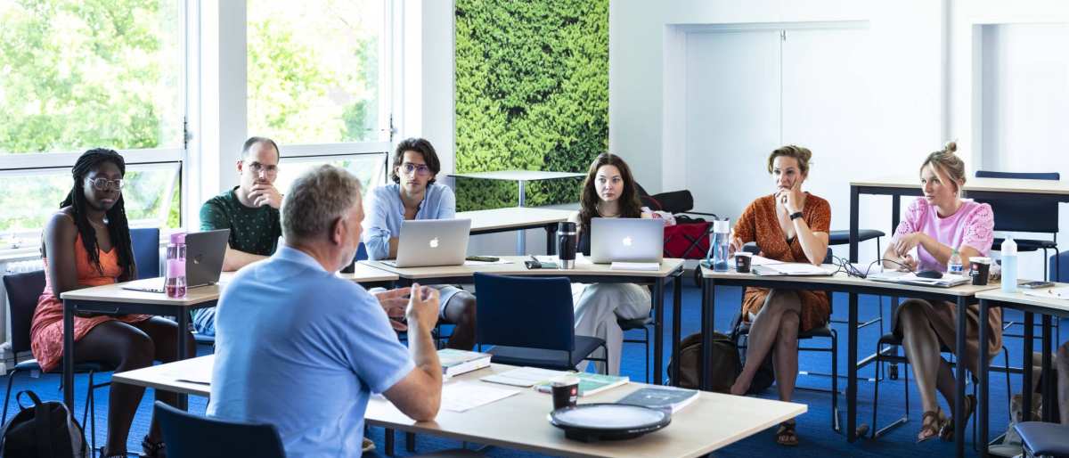 Studenten van de Master Social Work luisteren aandachtig terwijl de docent uitleg geeft.