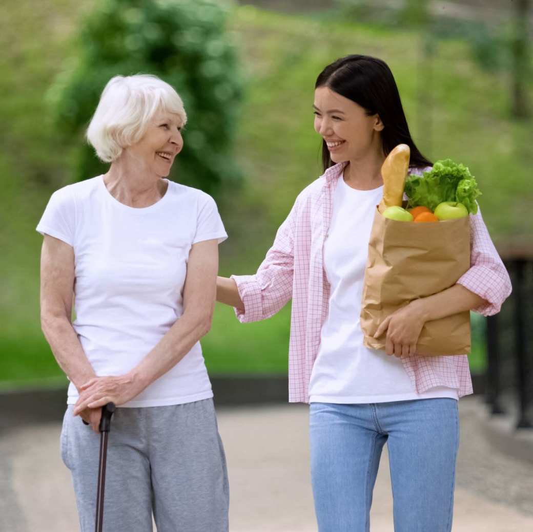 vrouw met stok met jonge vrouw met boodschappen in park