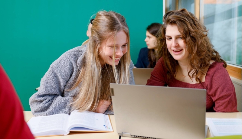 Studenten kijken lachend naar een iPad