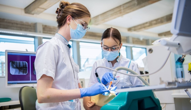 Studenten voeren een behandeling uit op een patient in een tandartsenpraktijk