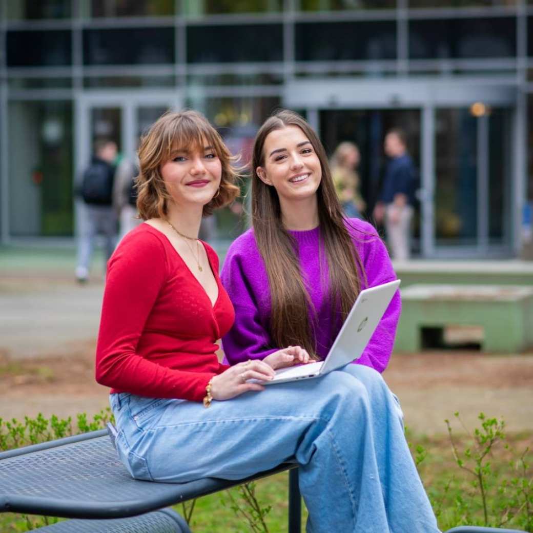Studenten van Learning and Development in Organisations voltijd kijken lachend in de camera buiten voor Laan van Scheut 10 in Nijmegen.