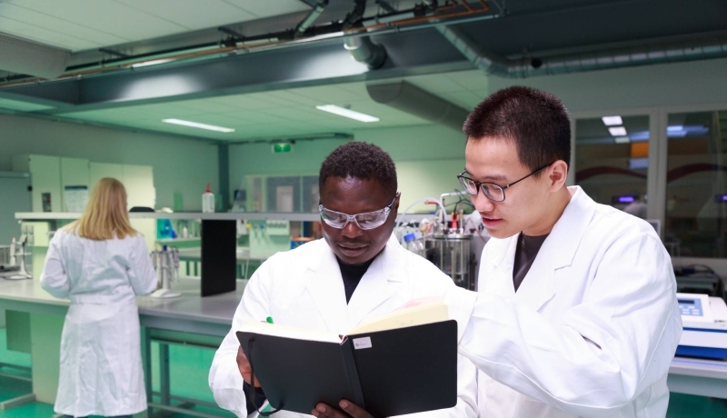 Studenten master Life Sciences Alain Barhasima en Dat Le werken in een biologielab. Op de rug Lisan Scholten