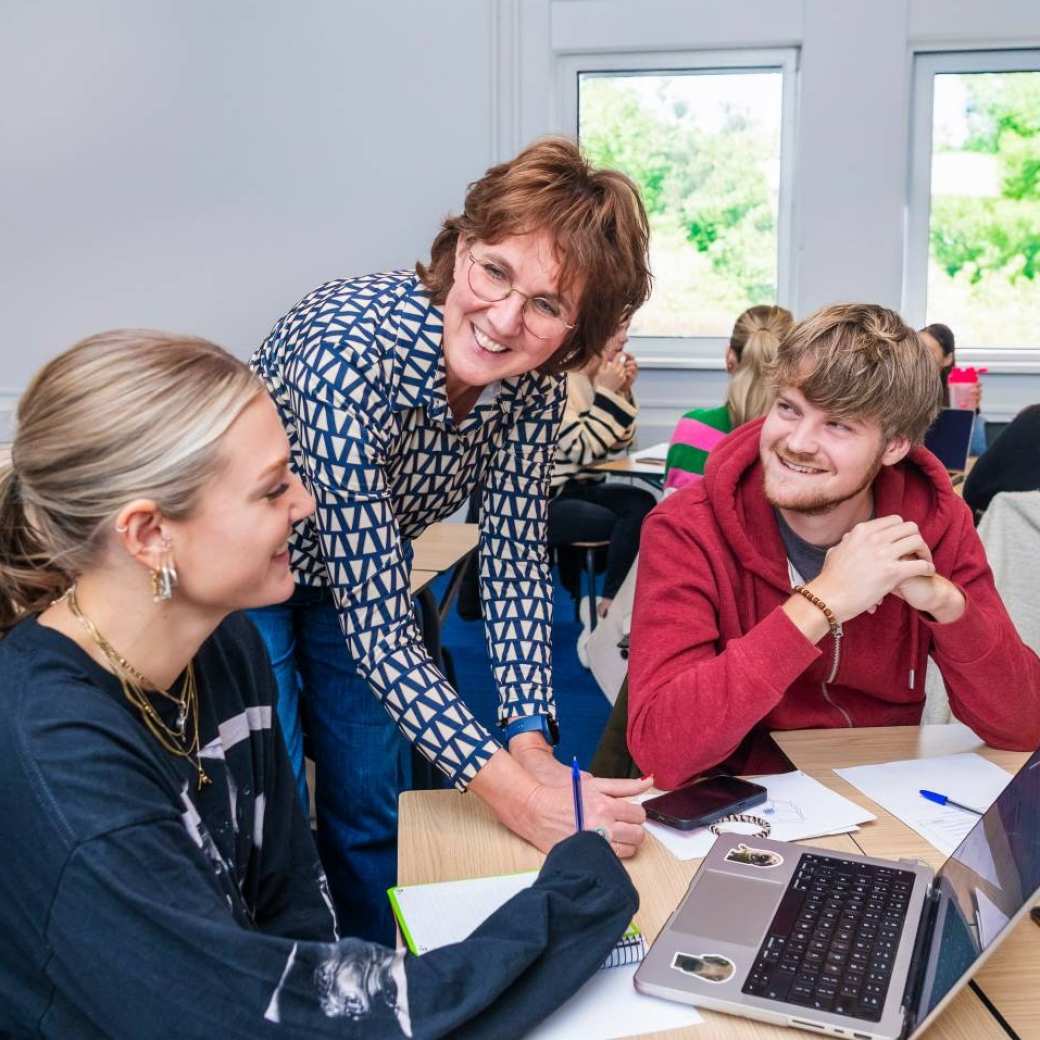 Leraar Fastswitch Social Work in overleg met 2 FastSwitchers in de klas.