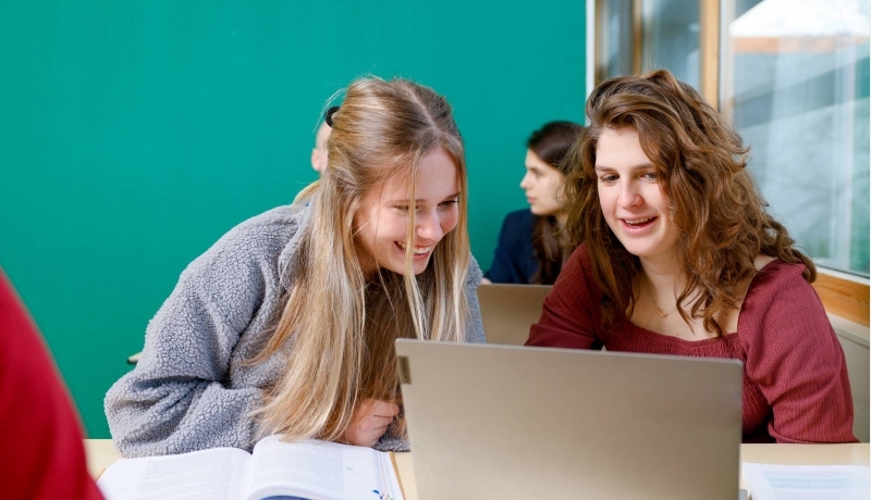 Studenten kijken lachend naar een iPad