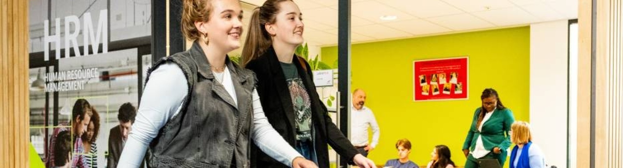 Studenten Human Resource Management (HRM) lopen op de gang voor de studio van de opleiding