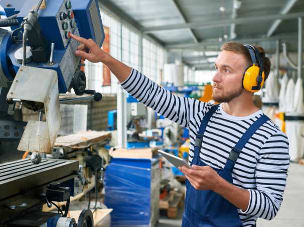 Jonge operator met gele gehoorbeschermers op de werkvloer van een moderne fabriek
