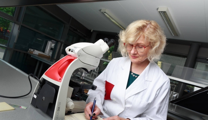 Post-hbo cursist Life Sciences aan het werk met een microscoop.