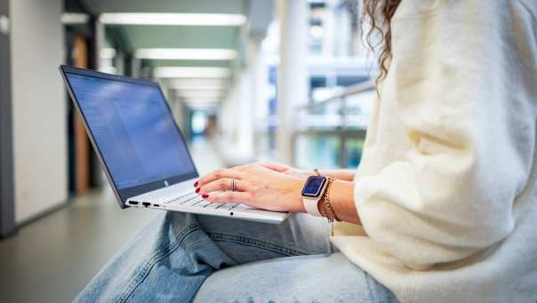 Student van de bachelor Commerciële Economie deeltijd, duaal in gang met laptop.