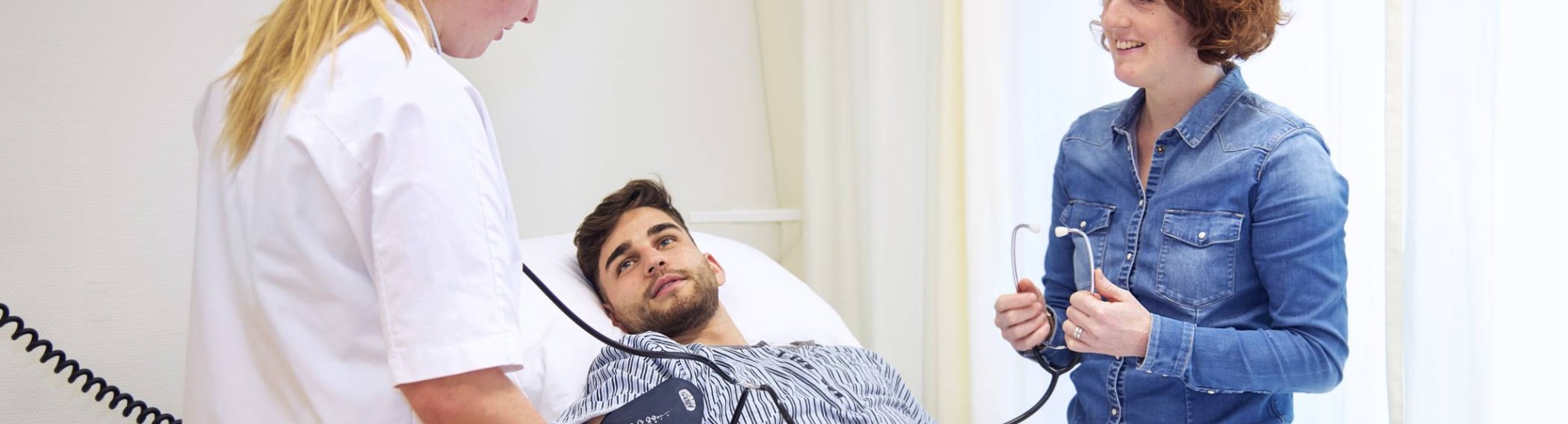 Voltijd student Verpleegkunde en docent aan het bed van patiënt meten bloeddruk-1