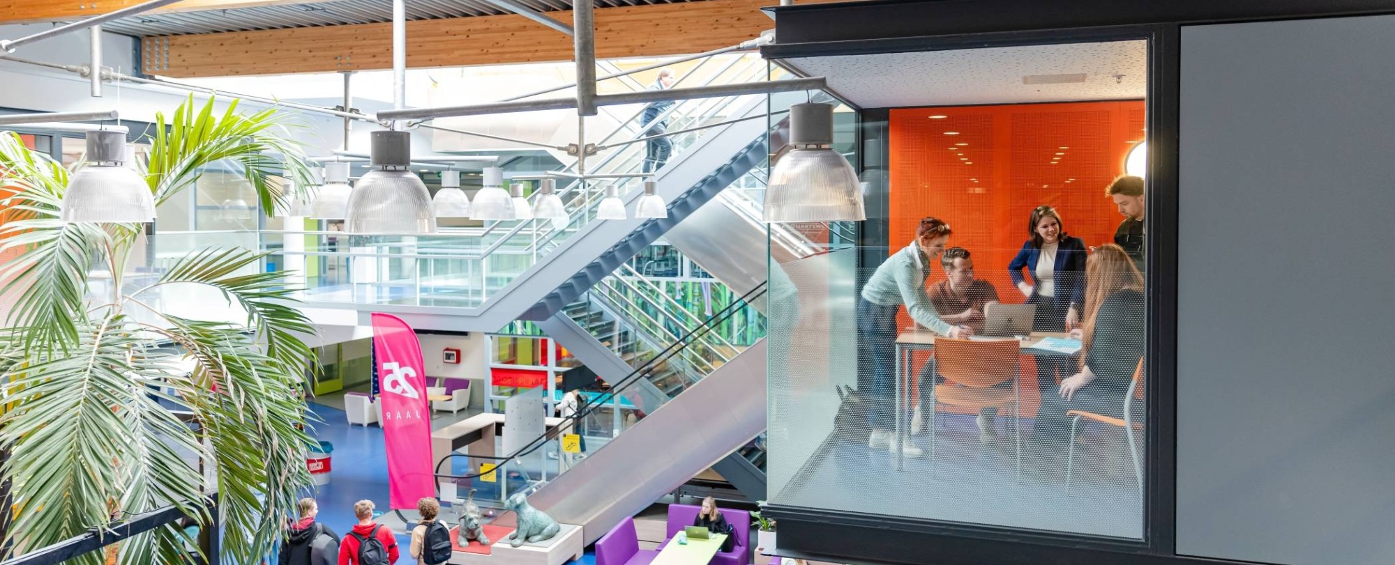 Een groepje studenten van de module Adviseren over leren in organisaties werken samen in een glazen overlegruimte op de HAN