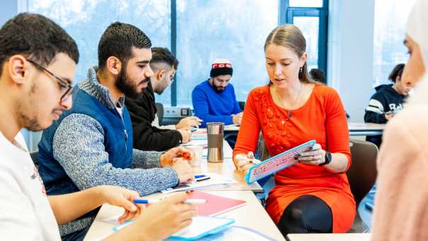Klas cursisten Nederlands A2 overlegt met een docent.