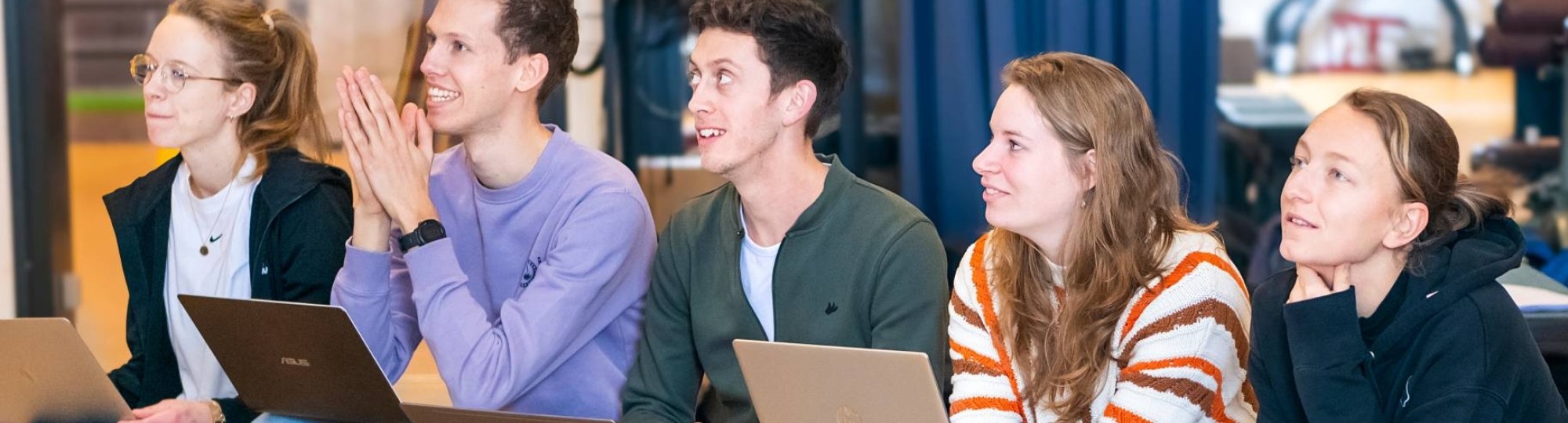 Studenten zitten op een gymbank, kijken erg hoopvol.