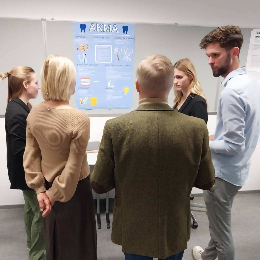 Groep mensen, waaronder studenten, kijkt naar presentatieposters