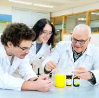 Twee studenten in een labjas kijken aandachtig naar een reageerbuisje.