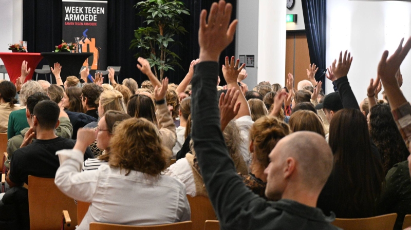 publiek met handen omhoog tijdens symposium beyond borders week tegen armoede