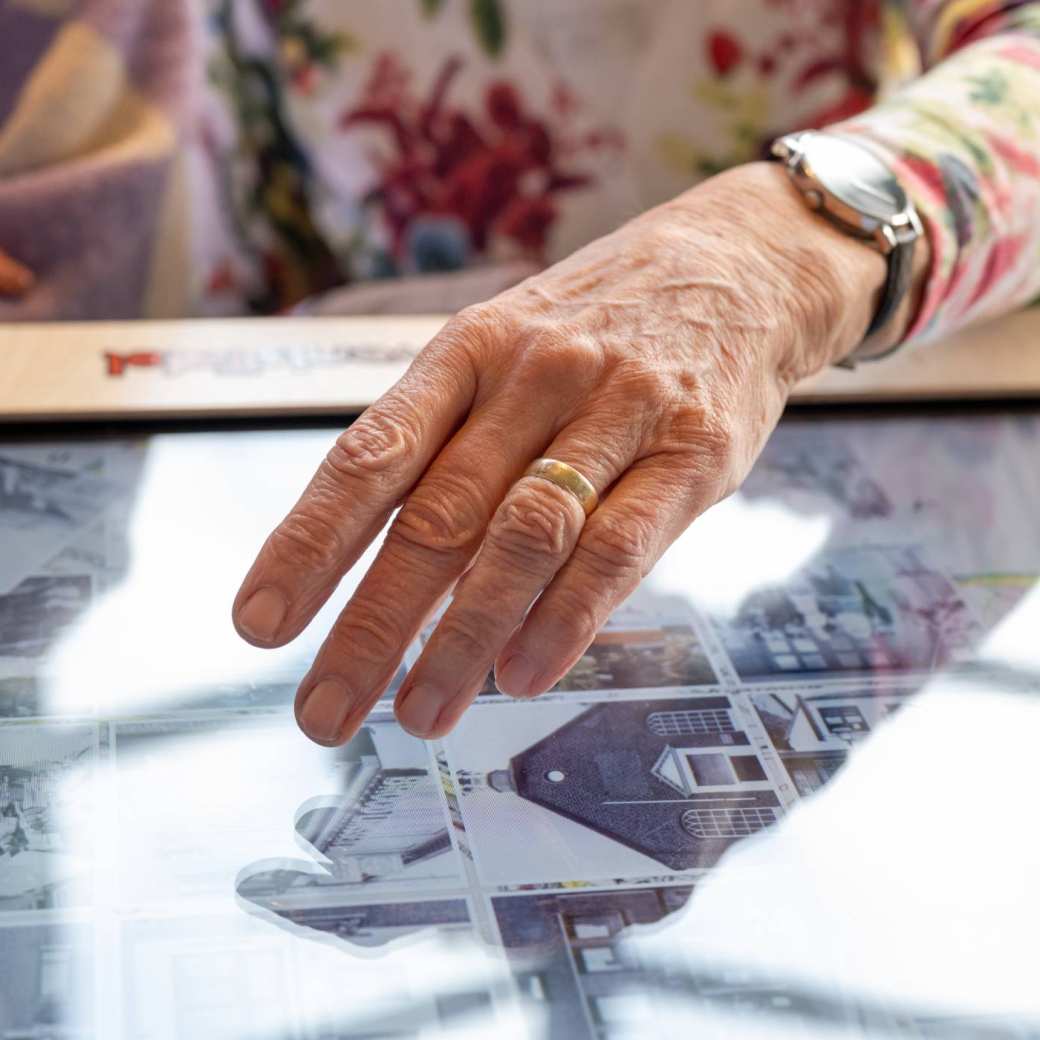 Hand van oudere raakt digitale belevenistafel aan