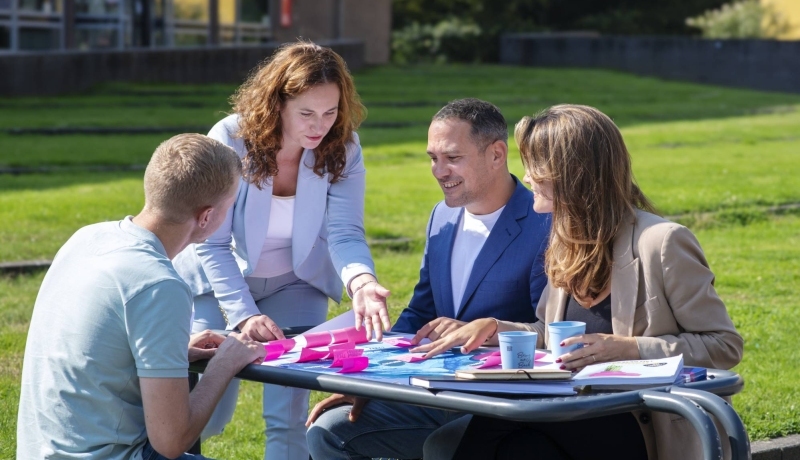 deelnemers master Business Sales samenwerken aan poster met post-its buiten op Ruitenberglaan 31 Arnhem.  