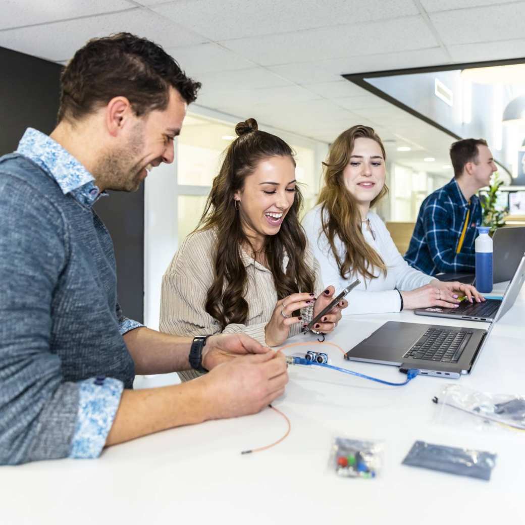 Studenten ICT in overleg met een docent.