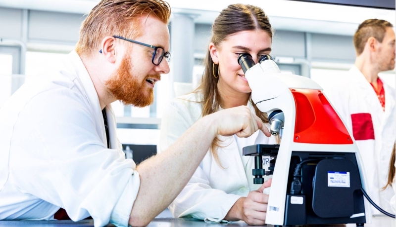 Docent geeft uitleg over de microscoop