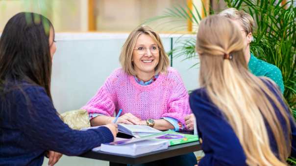 Student luistert en lacht en heeft roze shirt aan