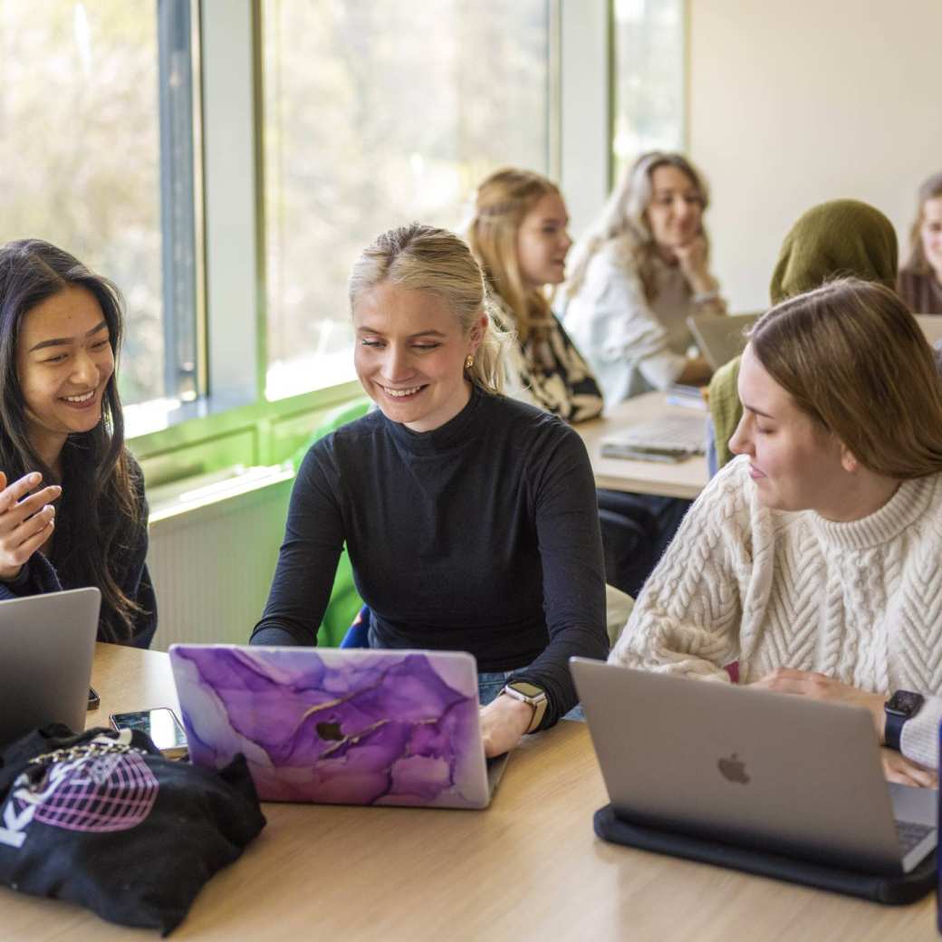 Health fotoshoot wijkcentrum studenten werken in groepjes aan tafels in een klas