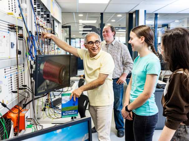 Een docent elektrotechniek geeft uitleg aan studenten in het hoogspanningslab.