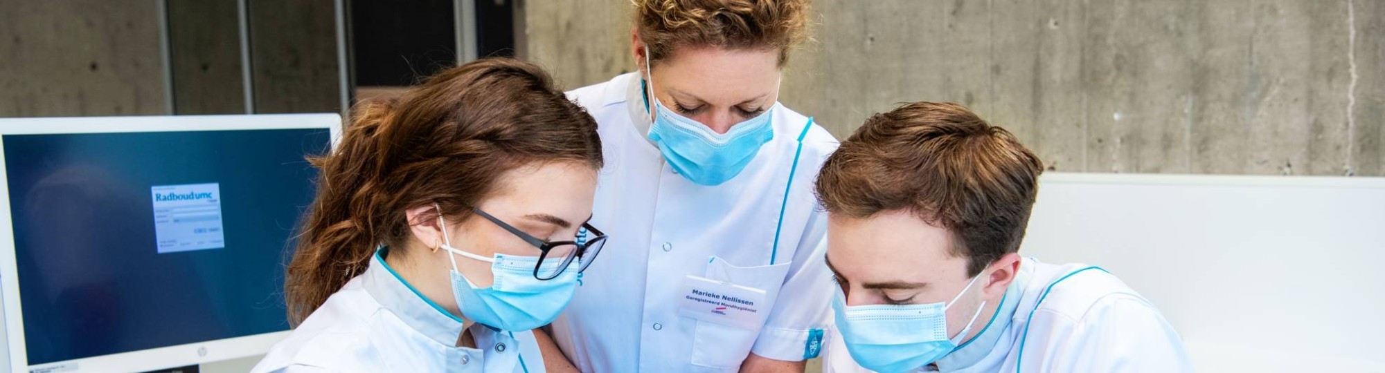 2 studenten en een docent kijken in de mond van een patient op een behandelstoel.