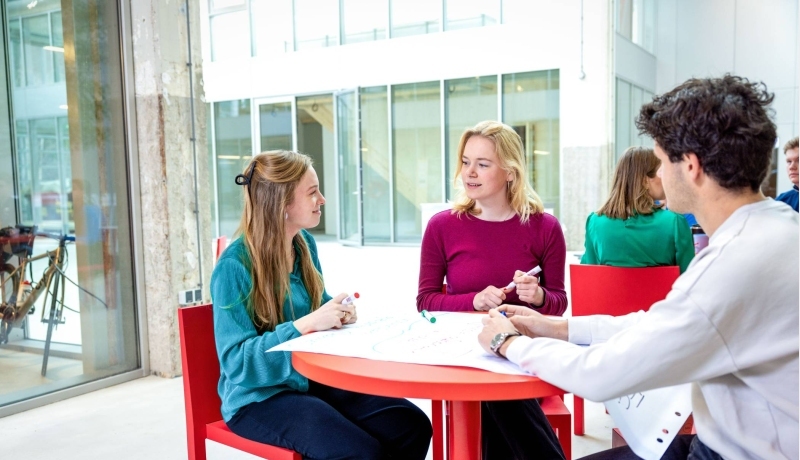 Lachende studenten aan tafel. Master Circulaire Economie 2024.