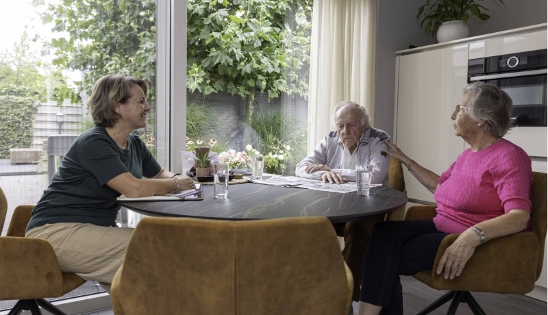 ouder echtpaar met zorgverlener aan tafel
