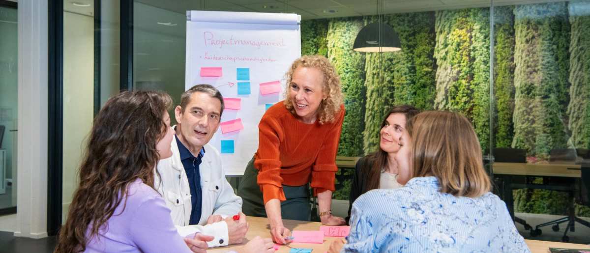 Deelnemers en docenten van de post-hbo Bedrijfskunde in overleg, lachend.